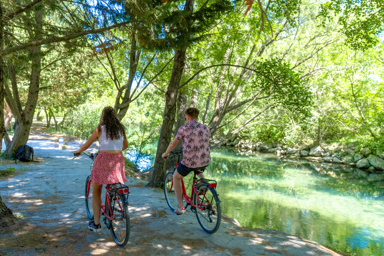Cyclists by a green river at CAPFUN Jantou campsite in LE THOR (84).