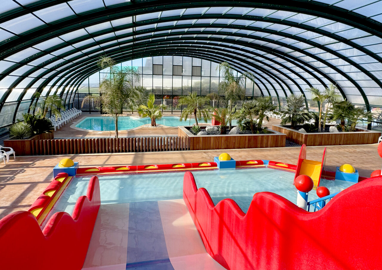 Indoor pool, slides, palm trees at CAPFUN Kervel campsite in PLONEVEZ PORZAY (29).
