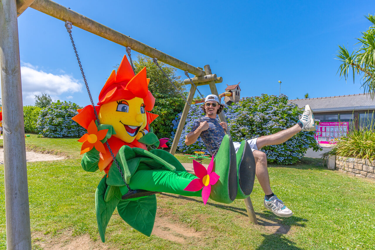 Mascot and young man on a swing at CAPFUN Kervel campsite in PLONEVEZ PORZAY.