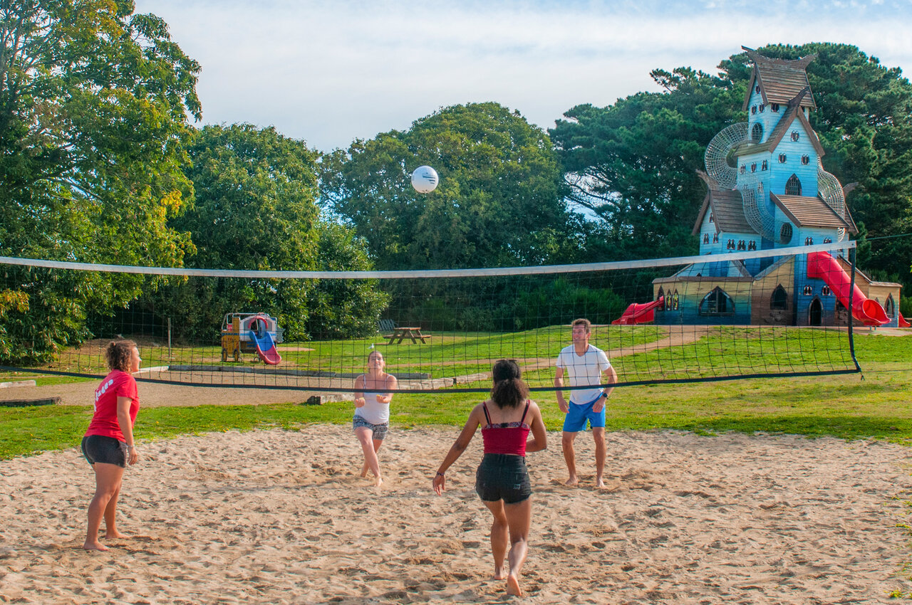 Beach volleyball court with players and play structure at CAPFUN Kervel campsite in PLONEVEZ PORZAY.