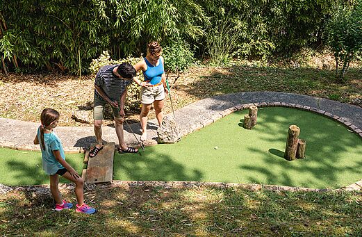 Family playing mini-golf on a green course at CAPFUN Lac des 3 Vall�es campsite in Lectoure (32).
