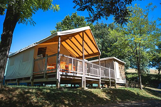 Tent lodge with wooden terrace at CAPFUN Lac des 3 Vall�es campsite in Lectoure (32).