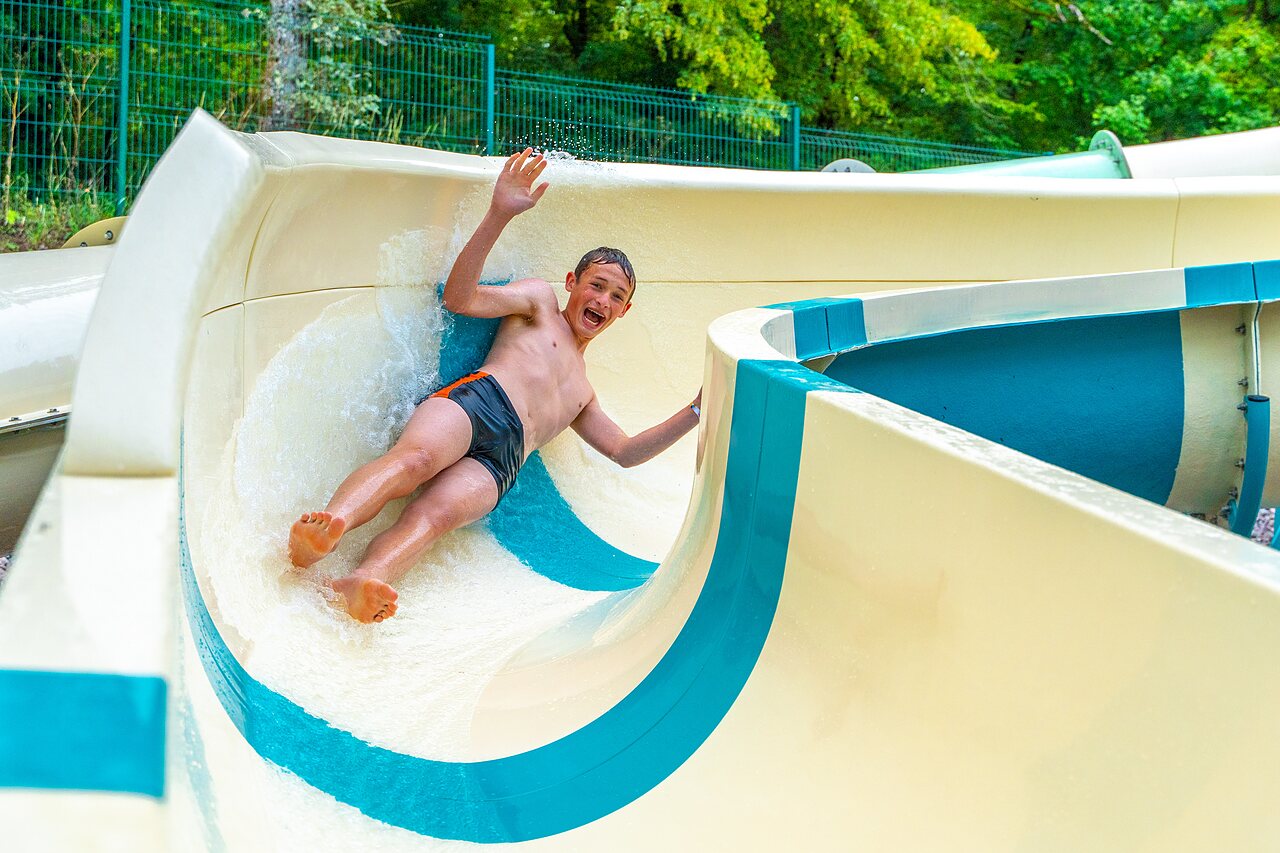 Water slide with smiling child at VAGUES OCEANES Lac de Panthier campsite in Vandenesse-en-Auxois (21).