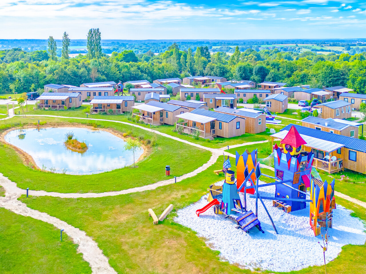 Colorful playground, pond and mobile homes at CAPFUN Lac de Ribou campsite in Cholet (49).
