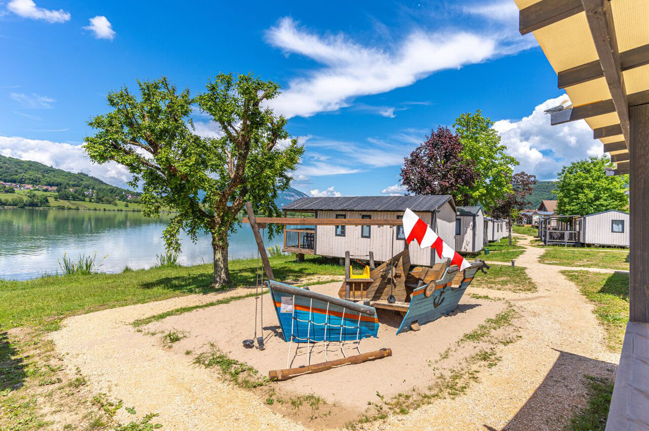 Playground boat, lake and mobile homes at CLICOCHIC Lac du Lit du Roi campsite in Massignieu-de-Rives (01).