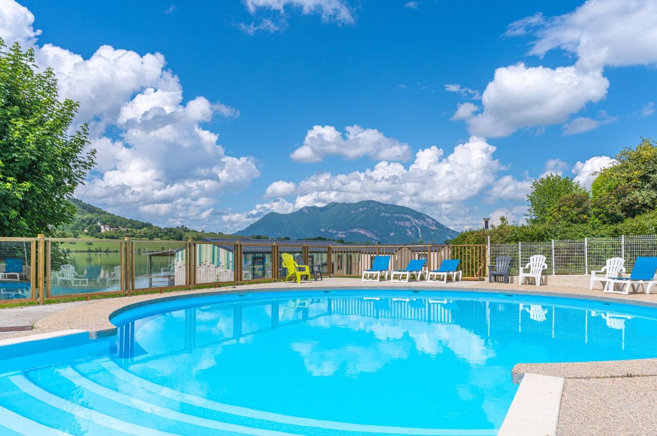 Swimming pool, sun loungers, lake and mountains at CLICOCHIC Lac du Lit du Roi campsite.