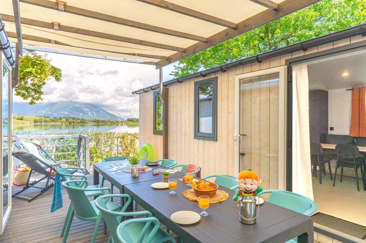 Spacious furnished terrace with lake and mountain views at CLICOCHIC Lac du Lit du Roi campsite in Massignieu-de-Rives.