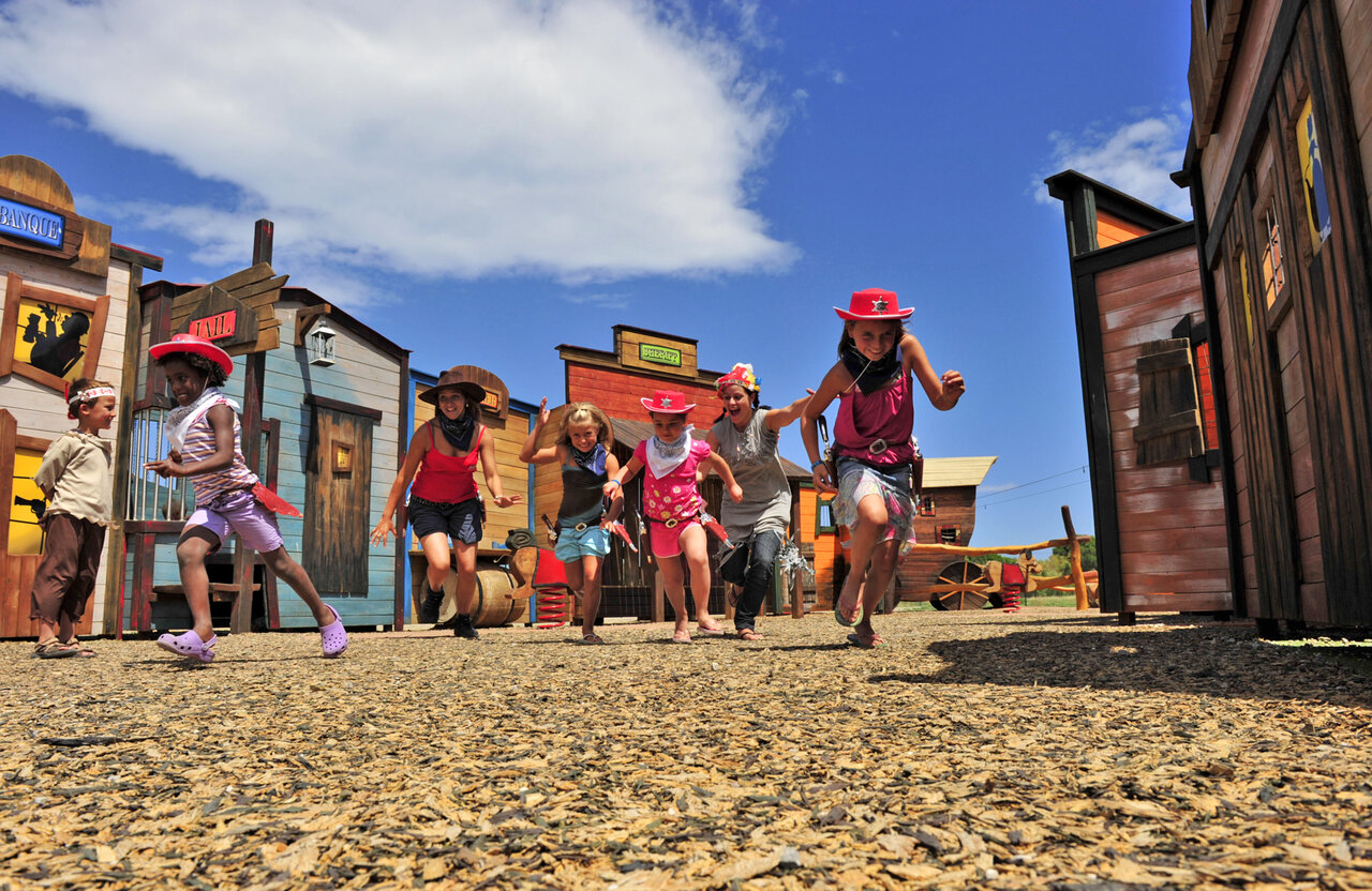 Children dressed as cowboys running in Western town, animation at CAPFUN Las Bousigues campsite.