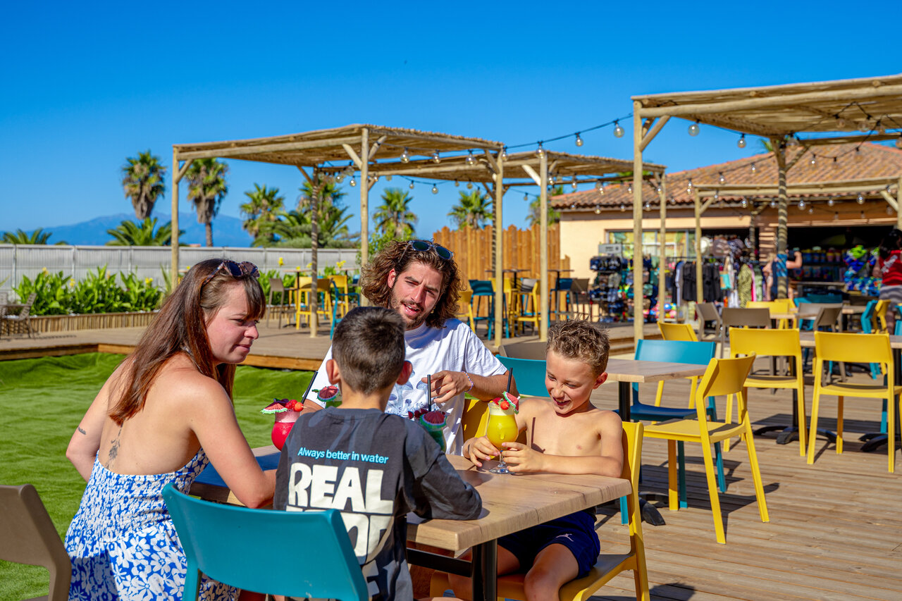 Smiling family enjoying drinks on the bar terrace at CAPFUN Las Bousigues campsite in Le Barcar�s (66).