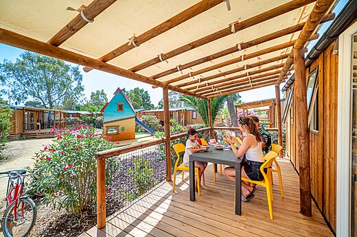 Family dining on Mobil-home terrace with children's play area at CAPFUN Las Bousigues campsite in Le Barcar�s (66).