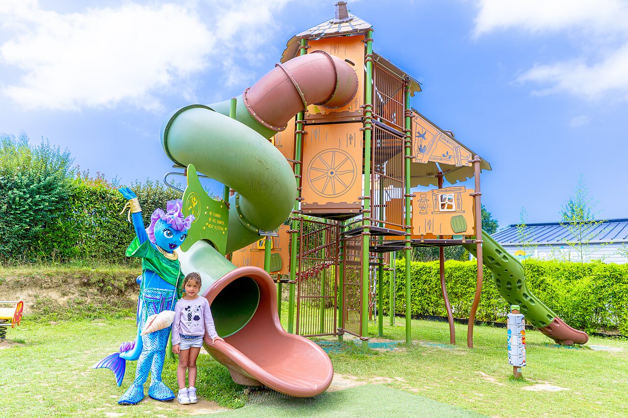 Playground with slides, child and mascot at VAGUES OCEANES Les Iles campsite.