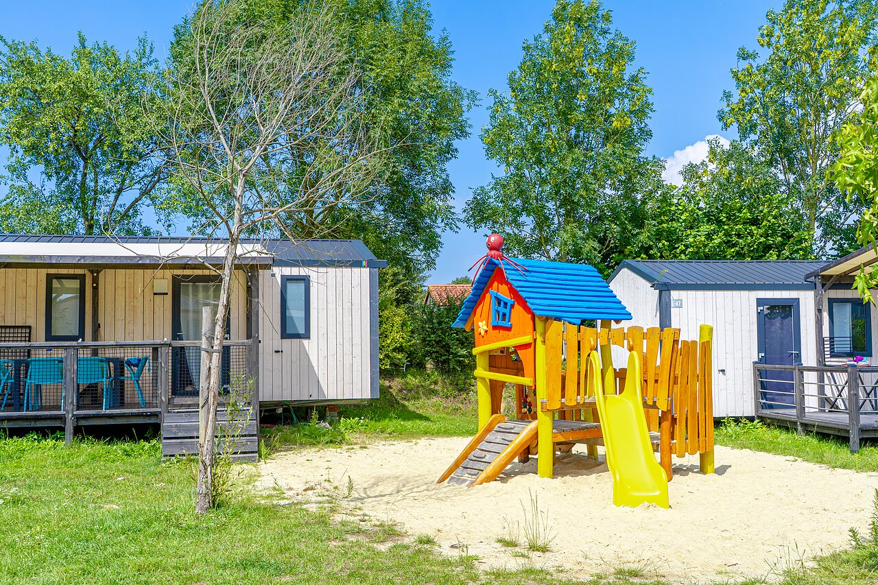 Playground, slide and Mobile homes at VAGUES OCEANES Les Iles campsite in Hudimesnil.