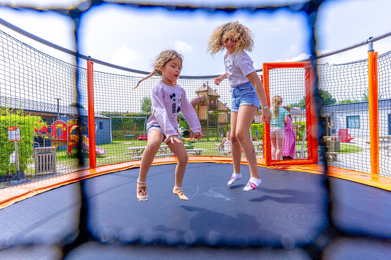 Children jumping on trampoline, playground at camping VAGUES OCEANES Les Iles in Hudimesnil (50).