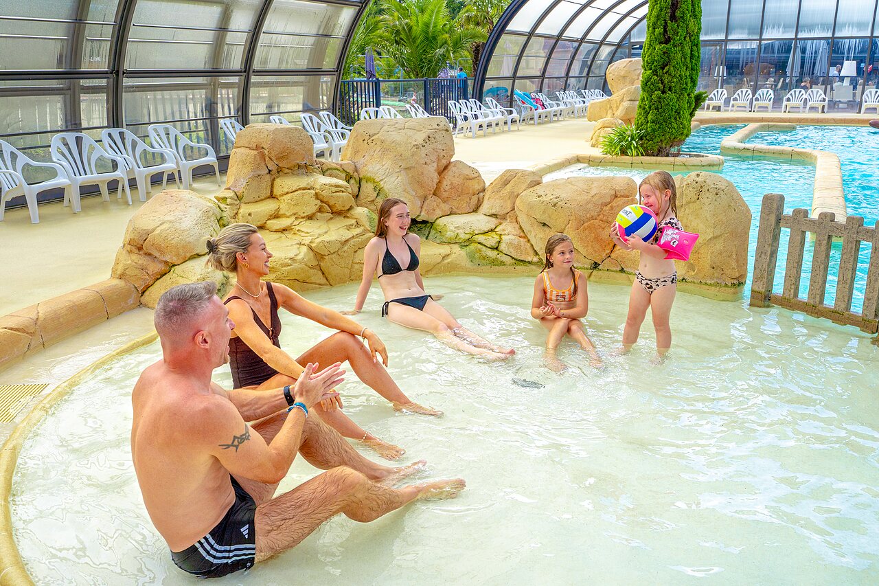 Covered paddling pool with family at VAGUES OCEANES Les Iles campsite in Hudimesnil (50).