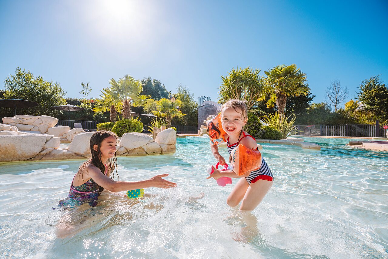 Smiling children, slide, swimming pool at VAGUES OCEANES Les Iles campsite Hudimesnil.
