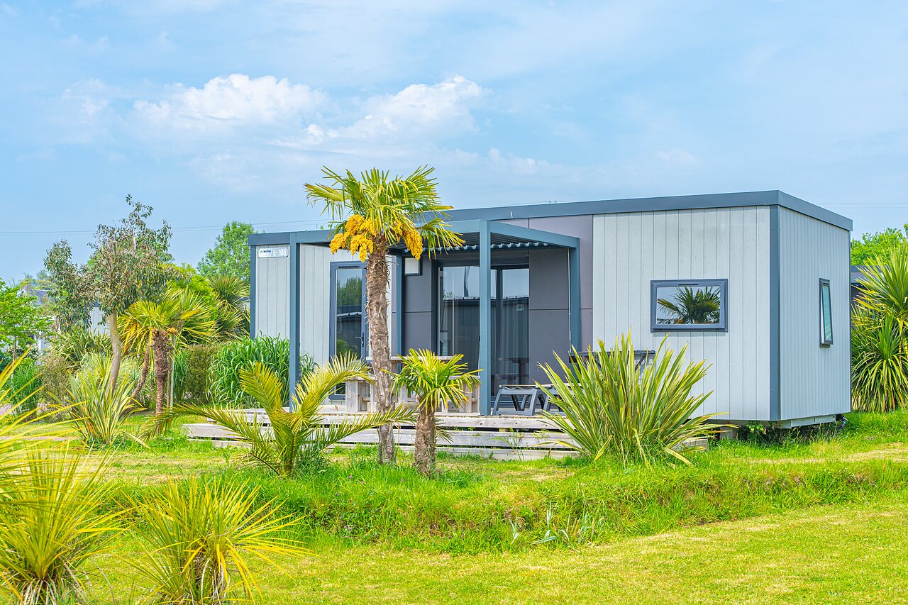Modern mobile home, terrace, palm trees at VAGUES OCEANES Les Iles campsite.
