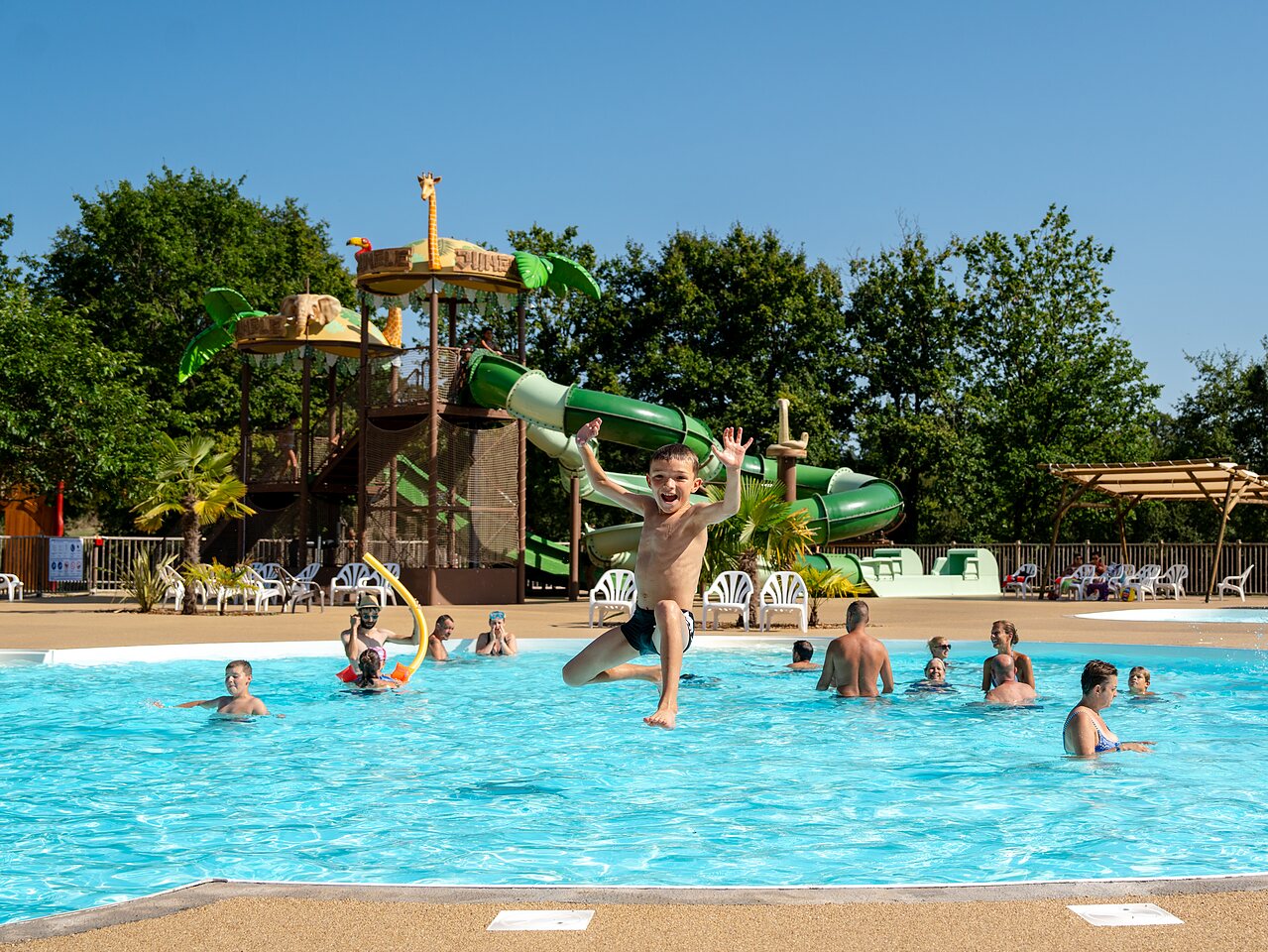 Outdoor pool, water slides, child jumping at CLICOCHIC Les Secrets de Padirac campsite (46).