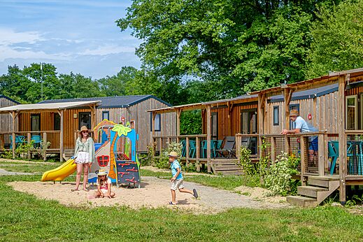 Wooden mobile homes and playground at CLICOCHIC Les Secrets de Padirac campsite (46).