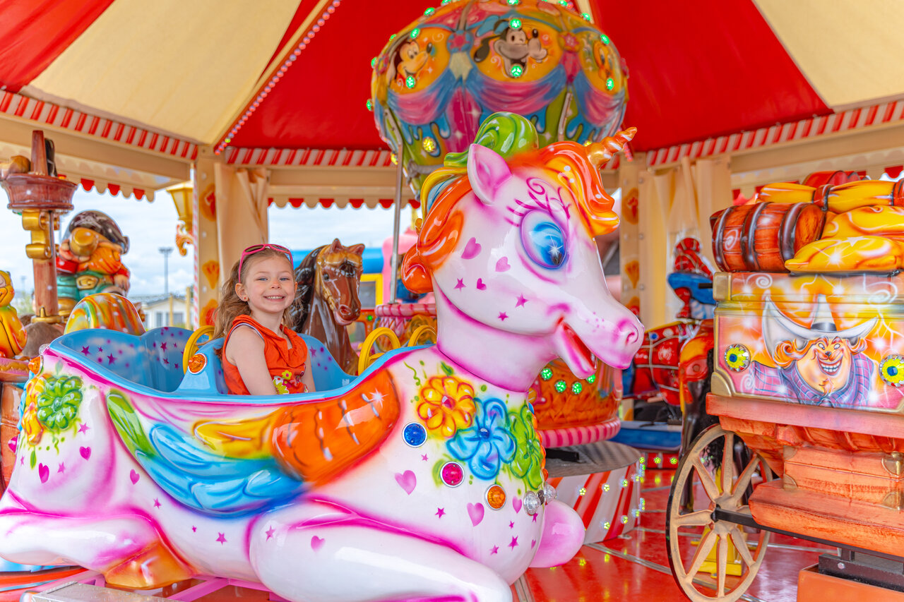 Smiling child on unicorn carousel ride at VAGUES OCEANES Licorne campsite in Dunkerque (59).