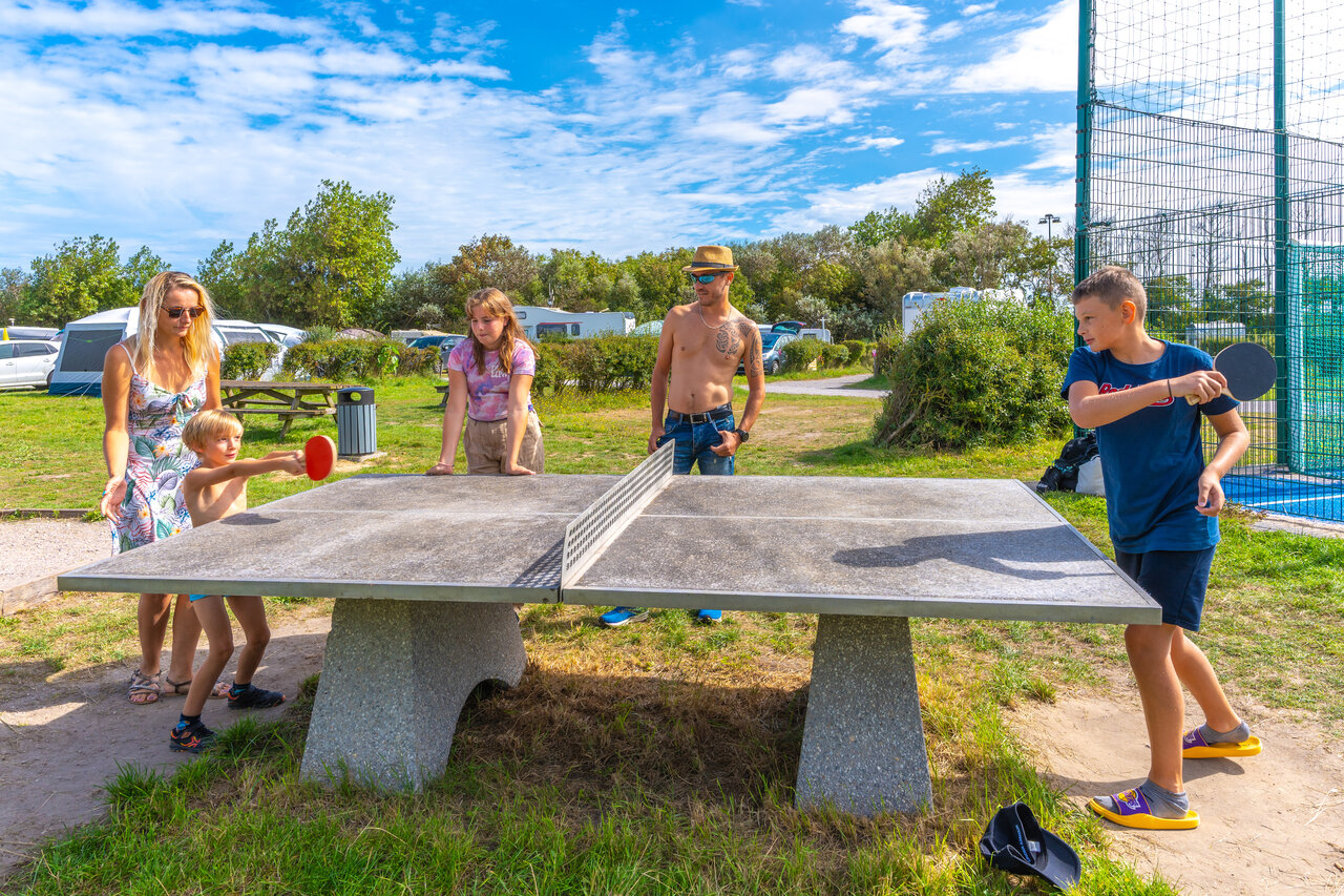 Family enjoying outdoor table tennis at VAGUES OCEANES Licorne campsite Dunkerque.