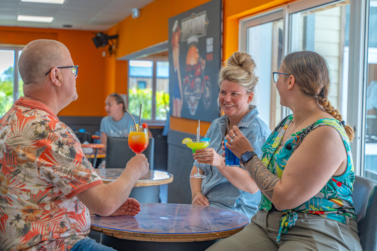 Guests enjoying colorful cocktails at the bar of camping VAGUES OCEANES Licorne in Dunkerque.