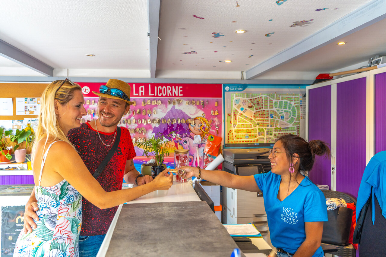 Couple receiving keys at the reception of VAGUES OCEANES Licorne campsite.