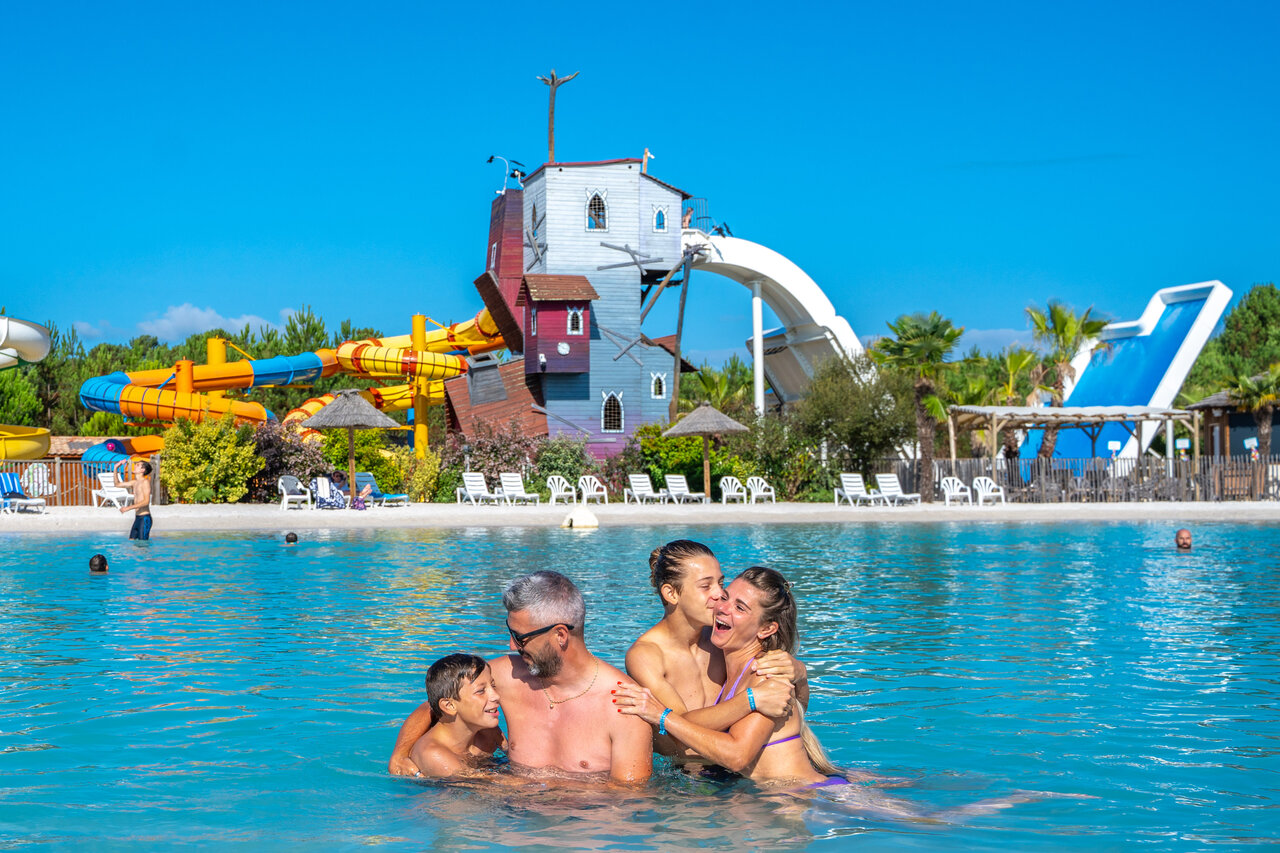 Smiling family in pool with giant water slides at CAPFUN Lila campsite in LINXE (40).