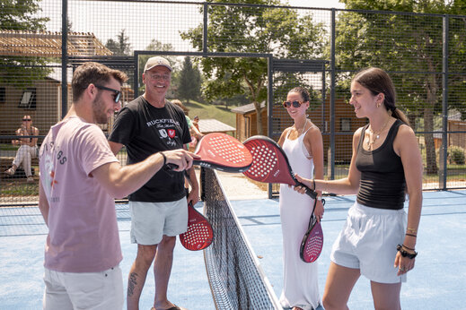 Smiling family playing padel on the multisport court at camping CLICOCHIC Linotte in Le Bugue (24).