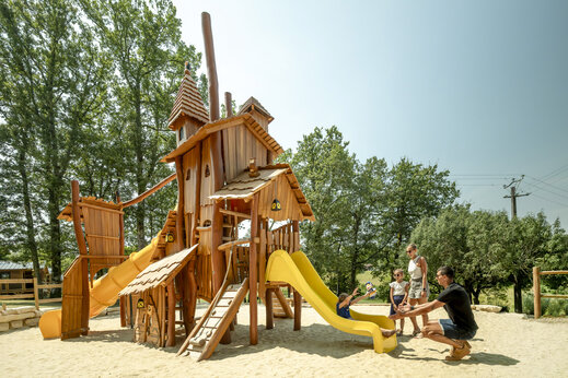 Large wooden playground with slides for children at CLICOCHIC Linotte campsite.