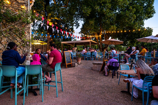 Lively restaurant and bar terrace in the evening at CLICOCHIC Linotte campsite in Le Bugue.