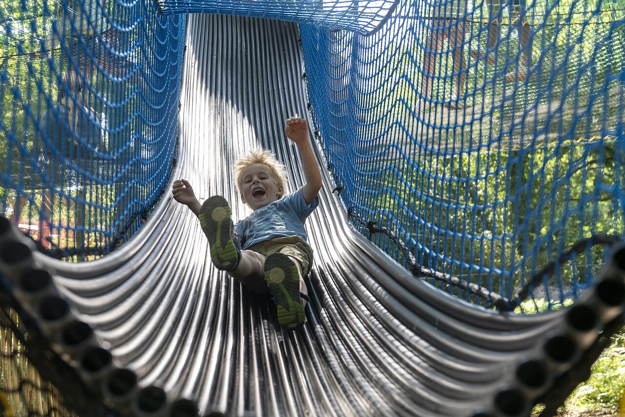 Smiling child on blue tube slide at CAPFUN Lodge campsite in SARZEAU (56).