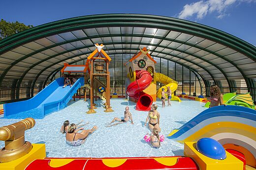 Covered swimming pool with slides and water games at CAPFUN Lodge campsite in SARZEAU (56).