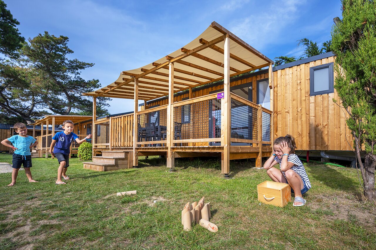 Children playing in front of modern mobile homes at CLICOCHIC Longchamp campsite in Saint Lunaire (35).