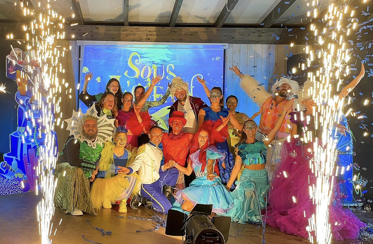 Artists in colorful costumes on stage with pyrotechnic effects at CLICOCHIC Longchamp campsite in Saint Lunaire (35).