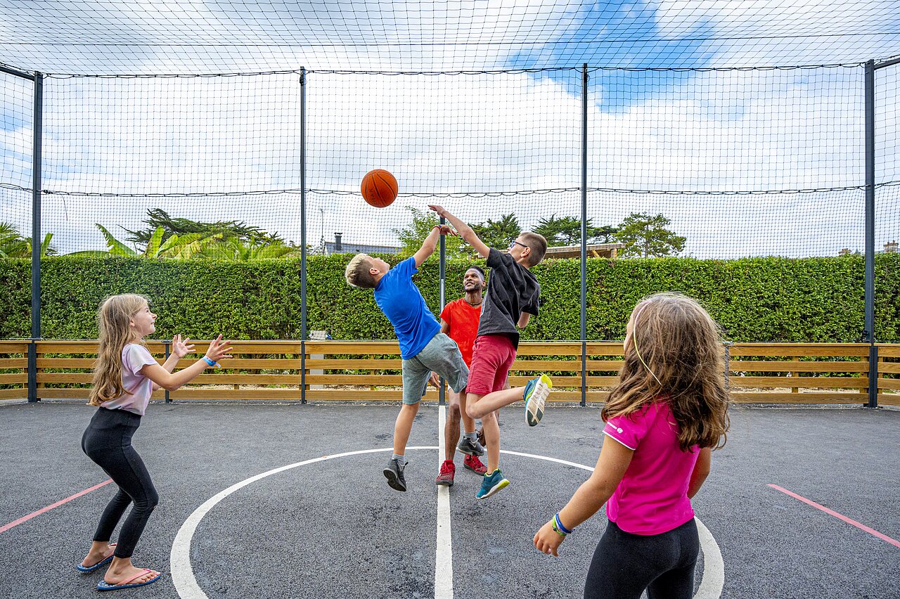 Children playing basketball on multisport court at camping CLICOCHIC Longchamp in Saint Lunaire (35).