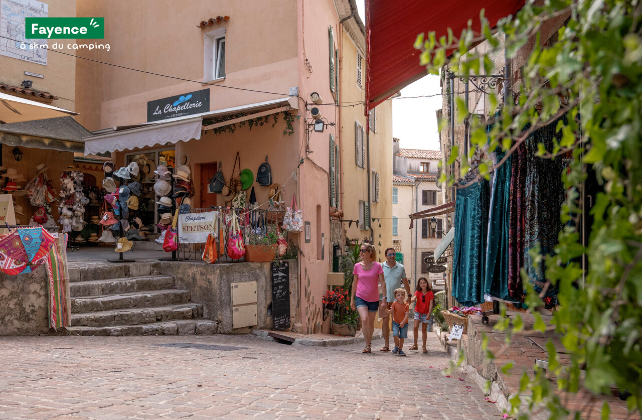 Family strolling through picturesque shopping street in Fayence, Provence.