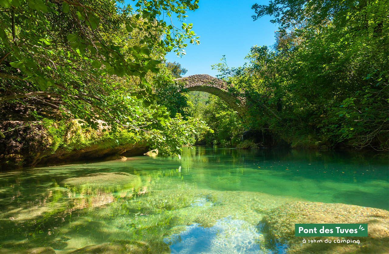 Pont des Tuves, turquoise river, historic stone bridge, lush nature.