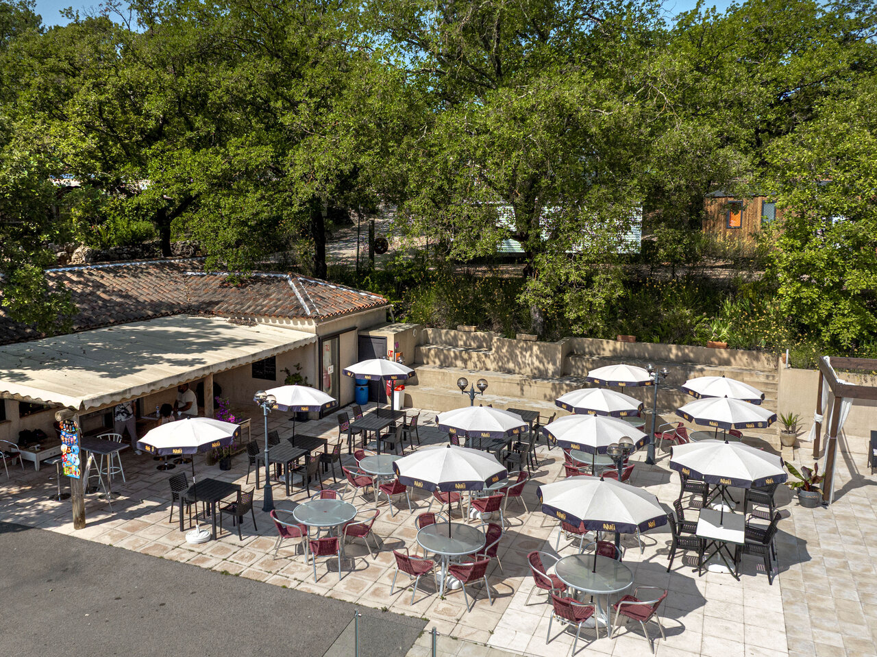 Outdoor restaurant terrace with parasols and tables at CLICOCHIC Lou Cantaire campsite in FAYENCE (83).
