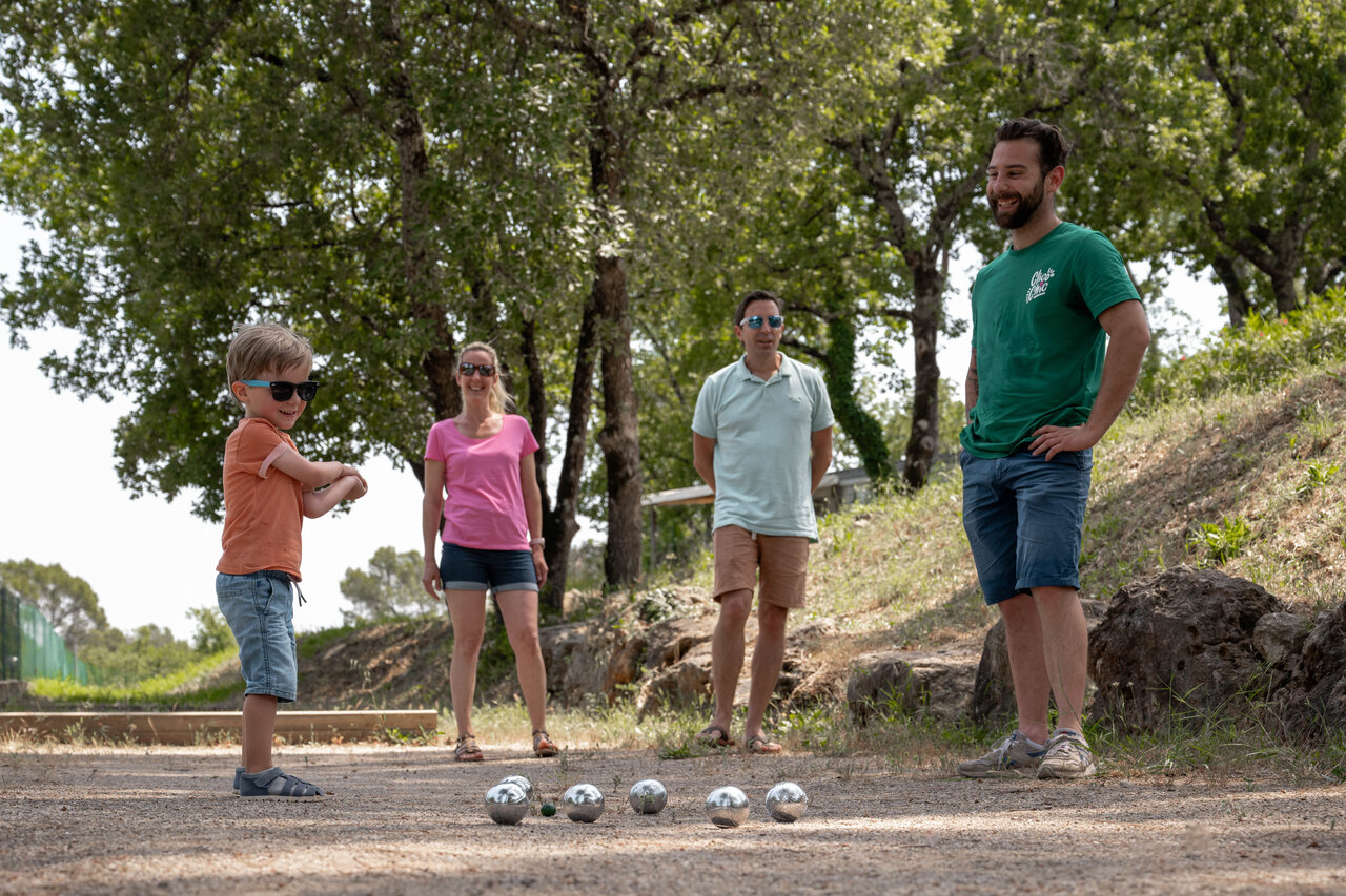 Family playing p�tanque on a shaded court at CLICOCHIC Lou Cantaire campsite in FAYENCE (83).