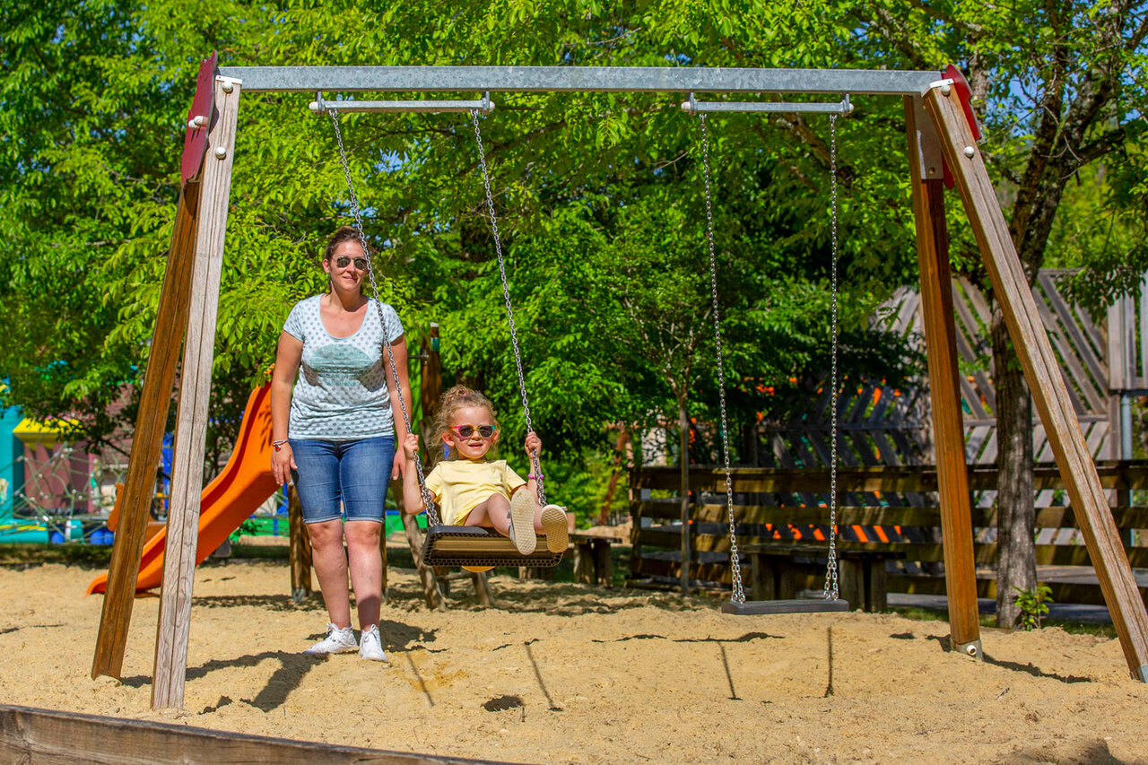 Child on swing, playground at CLICOCHIC Lou Castel campsite in Castelnaud-la-Chapelle (24).