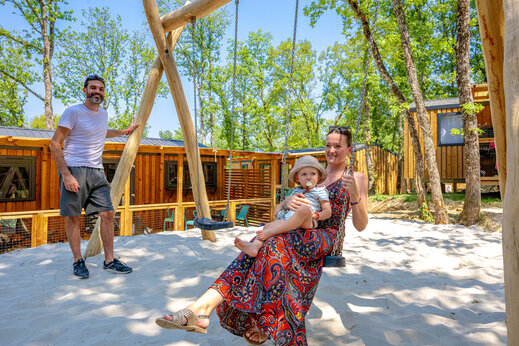 Family enjoying a swing in the playground with Mobile Homes at camping CLICOCHIC Lou Castel in Castelnaud-la-Chapelle (24).