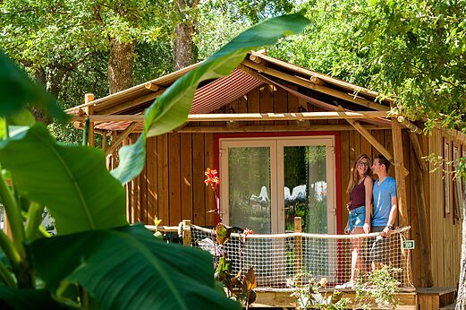 Wooden Mobil-home with terrace and couple at CAPFUN Lou Puntaou campsite in LEON (40).