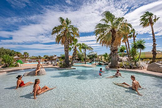 Outdoor pool, water slide, palm trees at CAPFUN Lou Village in Vendres (34).