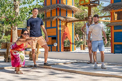 Family playing pétanque on a games court at camping CAPFUN Lou Village in Vendres (34).