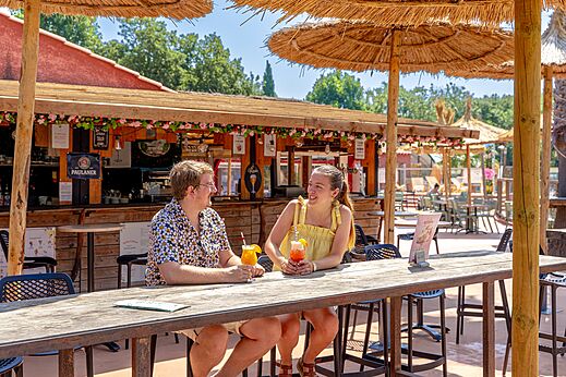 Smiling couple with cocktails at the bar-restaurant of CAPFUN Mael campsite in ARGELES SUR MER (66).