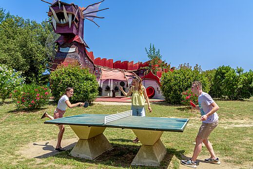 Young people playing table tennis in front of dragon structure at CAPFUN Mael campsite in ARGELES SUR MER (66).