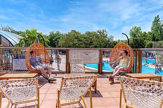 Comfortable hanging chairs and outdoor swimming pool at CAPFUN Mael campsite in ARGELES SUR MER (66).
