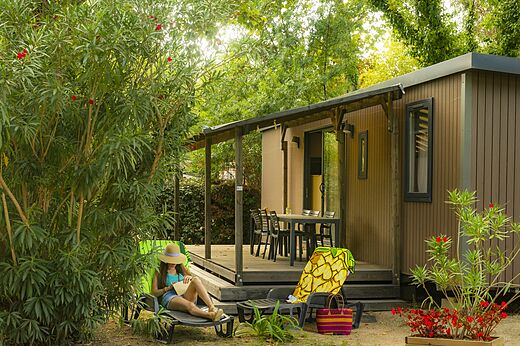 Modern mobile home with terrace and lush vegetation at CAPFUN Mael campsite in ARGELES SUR MER (66).