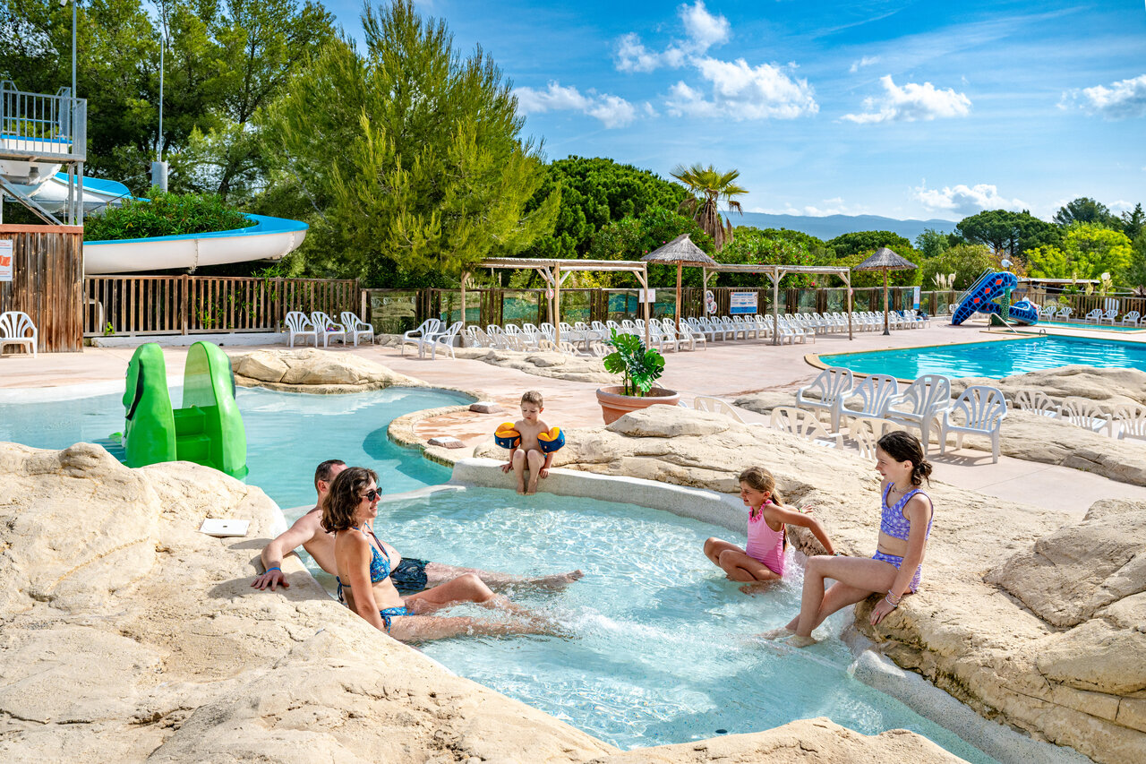 Family enjoying the fun swimming pool with slide at CAPFUN Malissonne campsite in LA CADIERE D'AZUR (83).