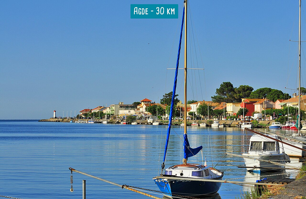 Port of Agde with boats, colorful houses and lighthouse, near the campsite.